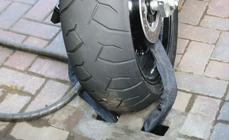 Chiếc xe máy được khóa bằng dây xích và ổ khóa lớn vào một cột cố định.