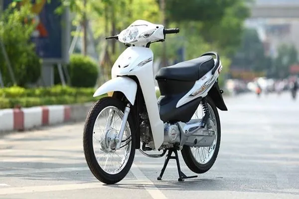 Học sinh nữ đang điều khiển xe Wave 50cc màu đỏ trong khu vực trường học, thể hiện sự nhỏ gọn và tính an toàn của phương tiện