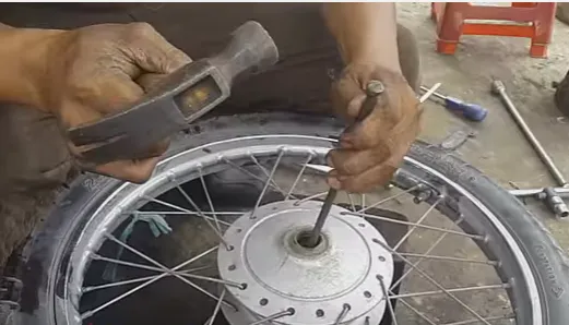 Sử dụng búa và cây đột để đẩy vòng bi cũ đã bị hỏng ra khỏi ổ trục khi bảo dưỡng hệ thống bánh xe