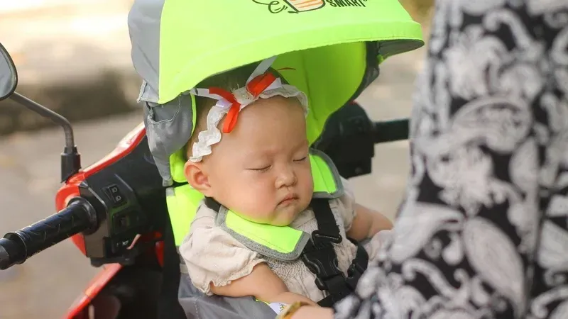 Sử dụng địu an toàn cho trẻ nhỏ quay mặt vào trong, giúp đảm bảo tư thế lái chuẩn và kỹ năng phòng vệ cho người điều khiển xe máy.