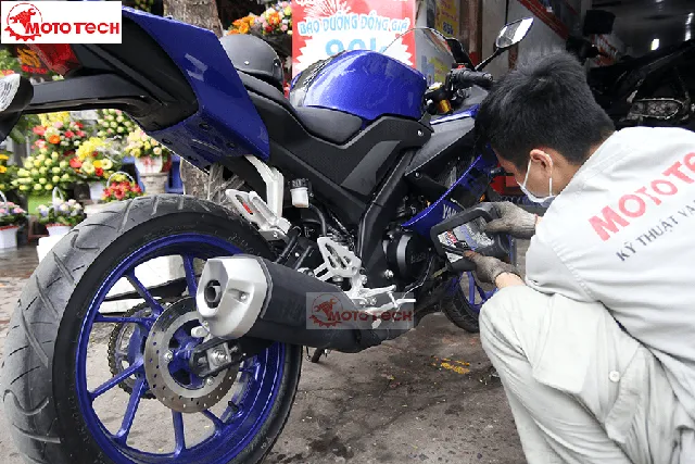 Xe thể thao Yamaha R15 đang được kỹ thuật viên kiểm tra chi tiết hệ thống giảm xóc và động cơ