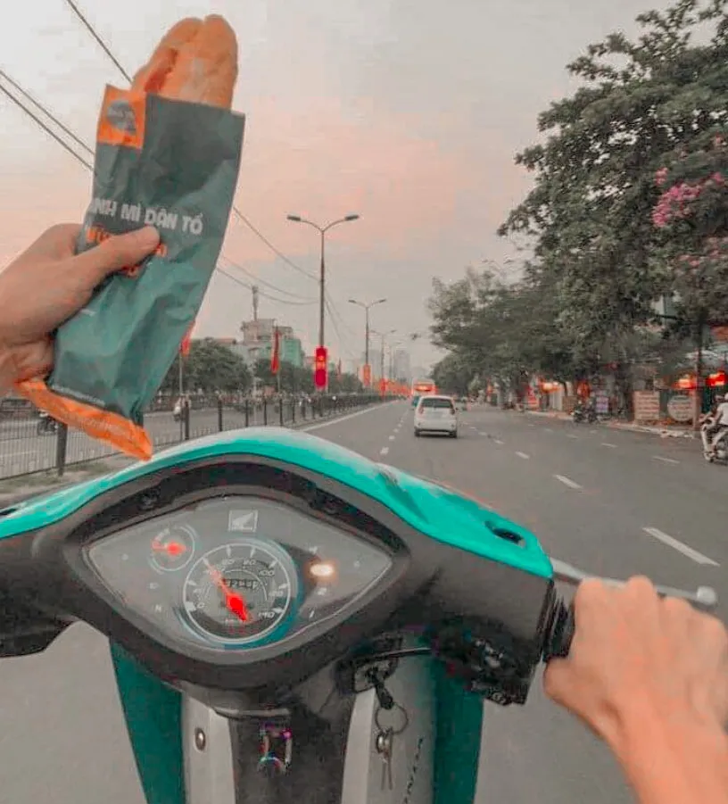 Thanh niên cầm bánh mì thực hiện bốc đầu xe Wave trên đường, thể hiện sự mạo hiểm và thiếu an toàn