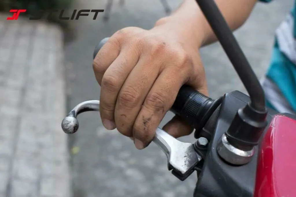 Người thợ sửa xe đang điều chỉnh phanh trước tang trống bằng tuốc nơ vít và cờ lê, tập trung vào ốc điều chỉnh độ rơ của phanh.