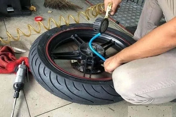 Người Thợ Đang Kiểm Tra Áp Suất Lốp Xe Máy, Đảm Bảo Độ Bền Sau Khi thay lốp xe wave hết bao nhiêu tiền