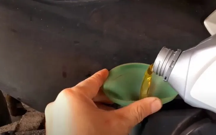 Sử dụng phễu và ca đong để đổ đúng 0.8 lít nhớt mới khi thay nhớt xe Wave Alpha