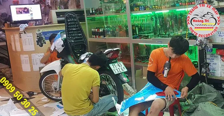 Nhân viên cửa hàng đang tiến hành xử lý các góc cạnh sau khi dán tem trùm cho xe Wave Alpha 2017