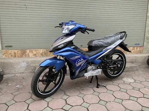 Mô tả hình ảnh: Chi tiết góc nghiêng phần đầu xe Exciter 50cc côn tay màu xanh dương, làm nổi bật thiết kế đèn pha và mặt nạ.