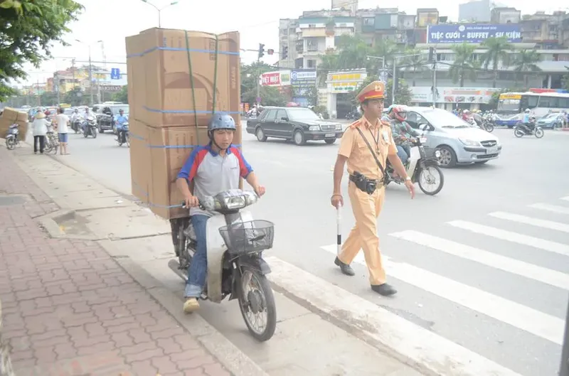 Alt text: Người lái xe máy chở máy giặt đã được cố định, tuân thủ quy định về kích thước hàng hóa