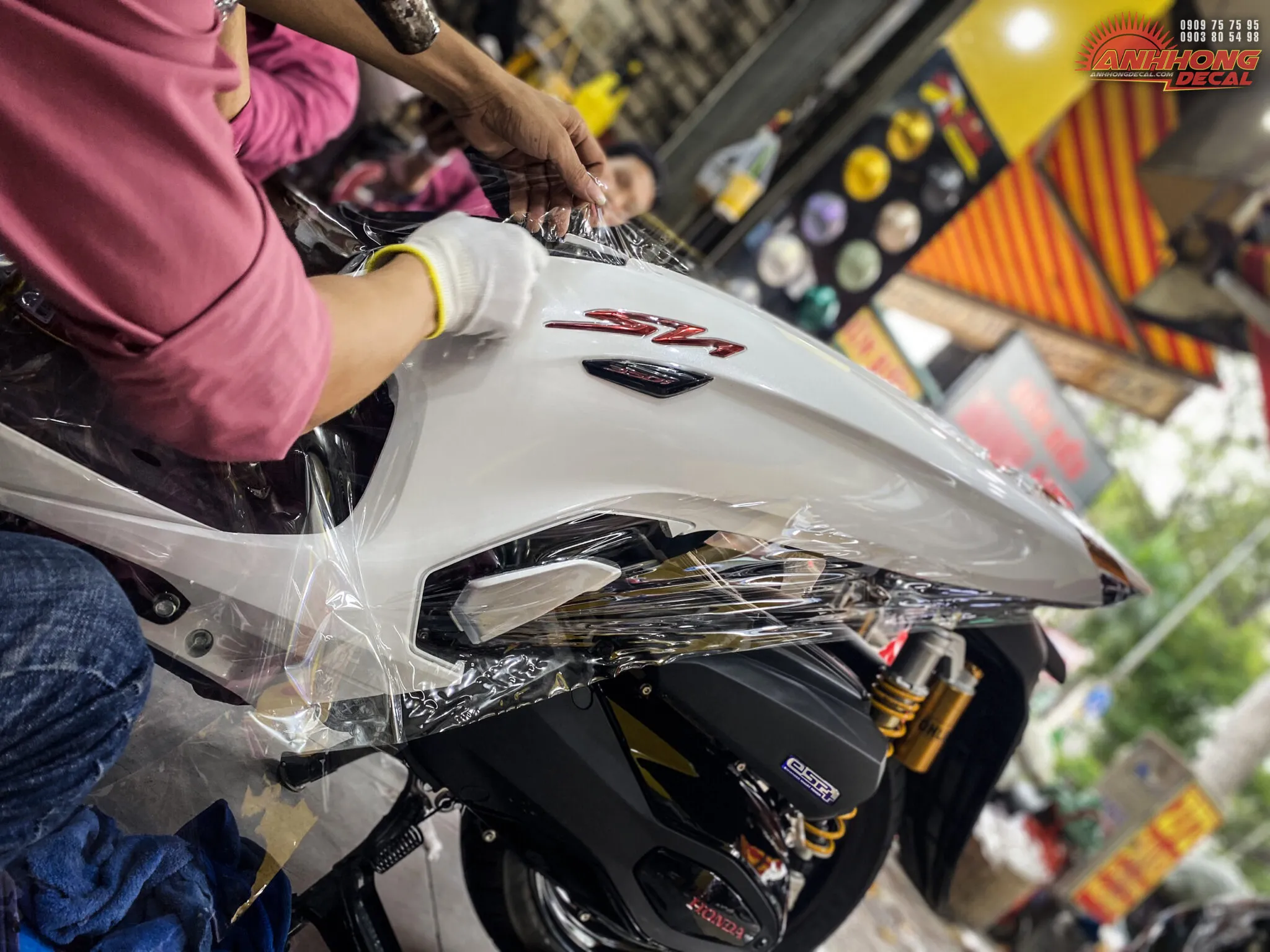 Một chiếc xe Sh350i đang được dán keo trong, thể hiện công đoạn xử lý bề mặt
