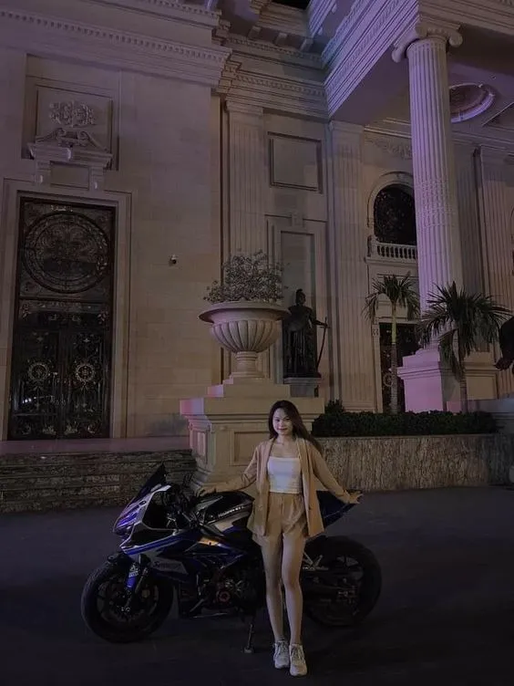 Nữ tạo dáng đứng bên hông xe, tôn lên đường cong cơ thể với trang phục bó sát