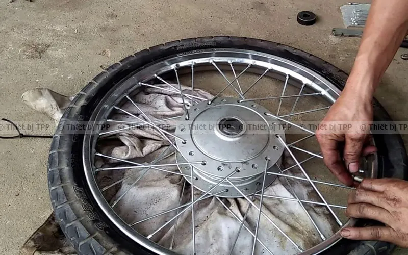Thao tác sử dụng móc lốp để tháo vỏ xe máy khỏi vành