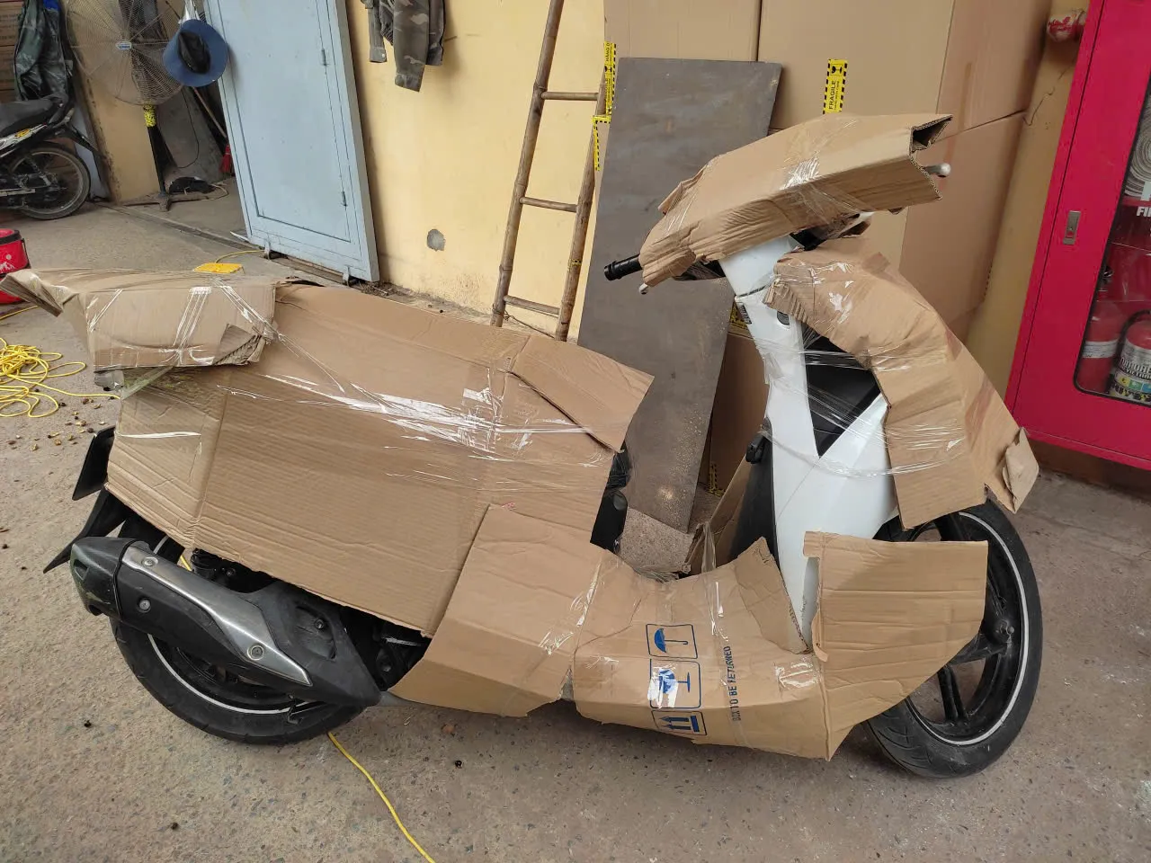 Nhân viên thực hiện bọc lót xe máy kỹ lưỡng bằng bìa carton